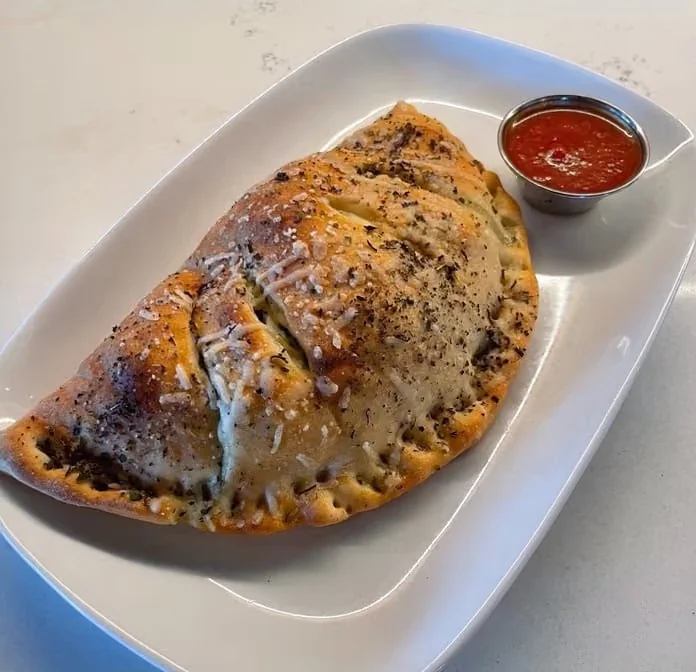 A baked calzone with marinara sauce